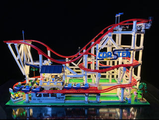 LEGO roller coaster set with red track, blue and tan structure, illuminated with custom lighting throughout the base and ride