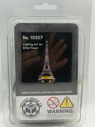 Eiffel Tower lighting kit in clear plastic packaging with illuminated tower display and warning labels.