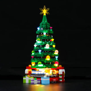 Green LEGO Christmas tree with illuminated multicolored lights, gold star topper, and wrapped presents at base.