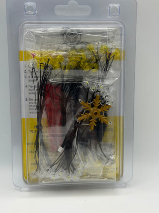 LED lighting kit with yellow bulbs, red and black wires, and gold snowflake connectors in clear plastic packaging.