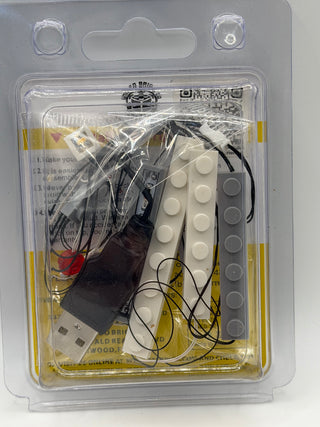 Custom lighting kit containing white and gray LED studs, black wiring, battery pack, and instruction sheet in clear plastic b