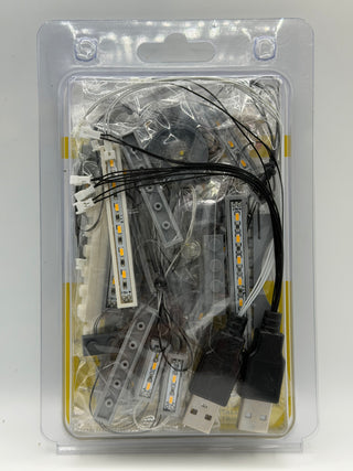 LED lighting kit containing multiple light strips with warm yellow LEDs, black wiring, and USB power connectors in clear blis