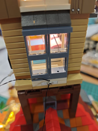Miniature building model with illuminated windows and vertical power connector base.