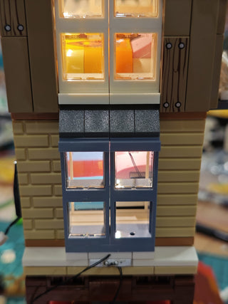 Modular lighting system with stacked compartments featuring illuminated orange and yellow panels, dark connector blocks, and 