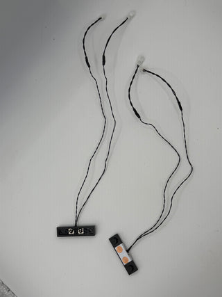 Two vertical power connectors with attached black wires and white terminal ends on white background.