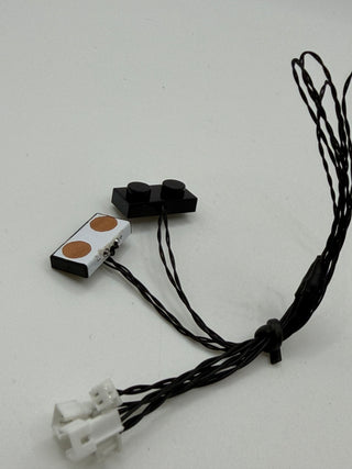 Two black vertical power connectors with copper contacts and white plastic connector blocks attached to black wires.