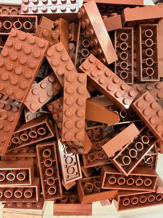 Assorted reddish-brown LEGO bricks and plates of various sizes stacked together.
