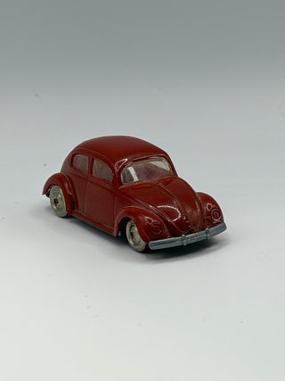 Dark red VW Beetle miniature vehicle with cream-colored wheels and metal bumper, shown from three-quarter view.