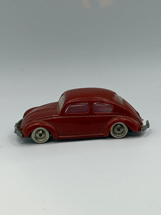 Dark red VW Beetle miniature model with white-wall tires and metal bumpers on gray background.