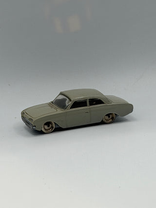 Light gray die-cast Ford Taunus sedan model with black windows and metal wheels, shown from the side.